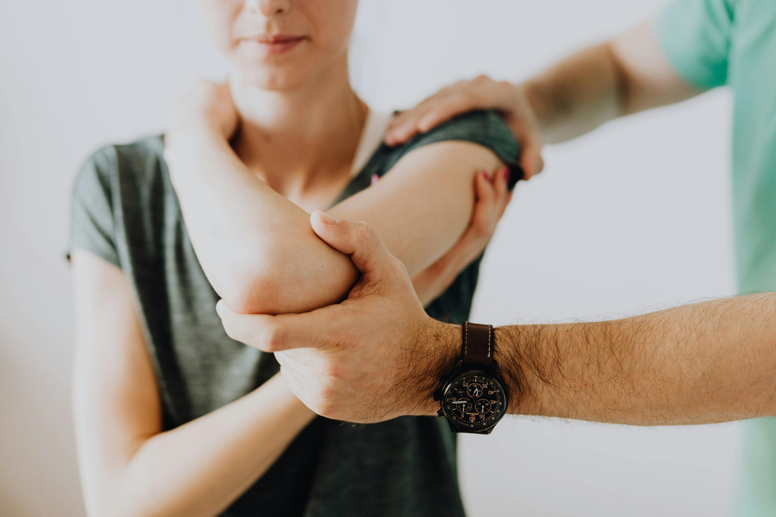 A medical worker adjusting a patient's arm in a clinic setting