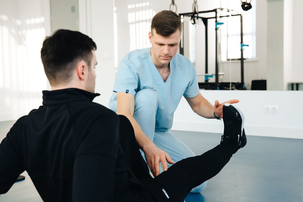 A physiotherapist assists a male patient during a rehabilitation session in a modern clinic.